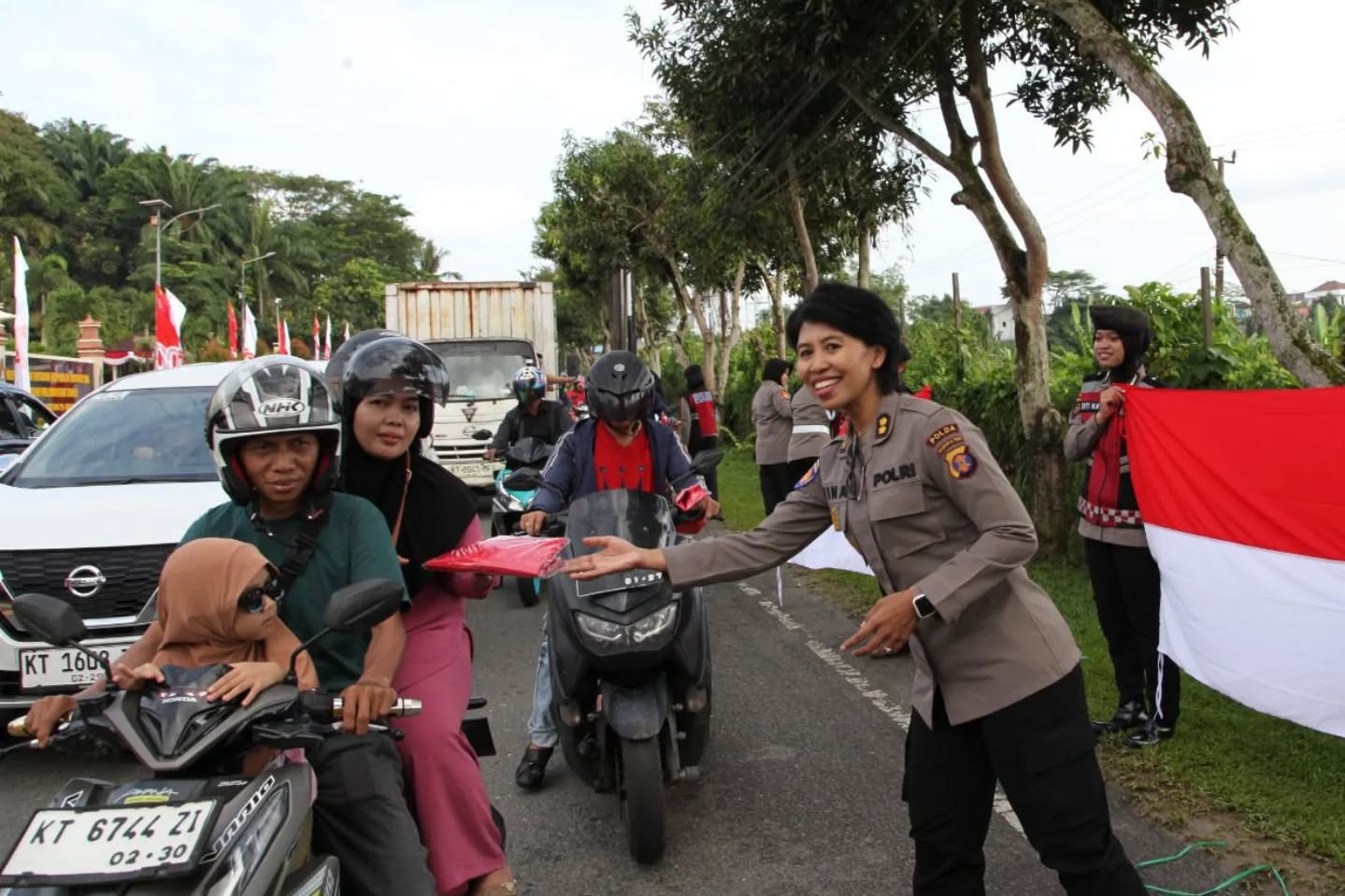 Polisi Wanita (Polwan) Polda Kaltim menggelar aksi pembagian ratusan Bendera Merah Putih kepada pengendara di Jalan Syarifuddin Yoes, tepat di depan Mapolda Kaltim, Kamis (14/8/2025).