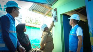 Petugas PLN memasang sambungan listrik baru di rumah warga pra sejahtera melalui program Light Up The Dream.