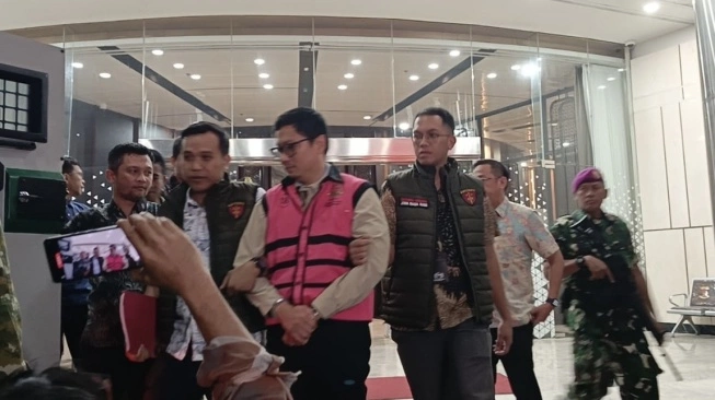 Komisaris Utama PT Yasa Artha Trimanunggal (YAT) Andrew Mulyono alias AM mengenakan rompi tahanan Kejaksaan Agung usai ditetapkan sebagai tersangka baru dalam kasus dugaan korupsi tata kelola Program Makan Bergizi Gratis (MBG). [Suara.com/Faiqh]