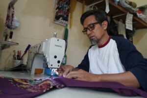 Irwan, pemilik usaha Penjahit Qalbu di Balikpapan Timur, mengerjakan pesanan dengan dukungan bantuan peralatan dari YBM PLN UID Kaltimra