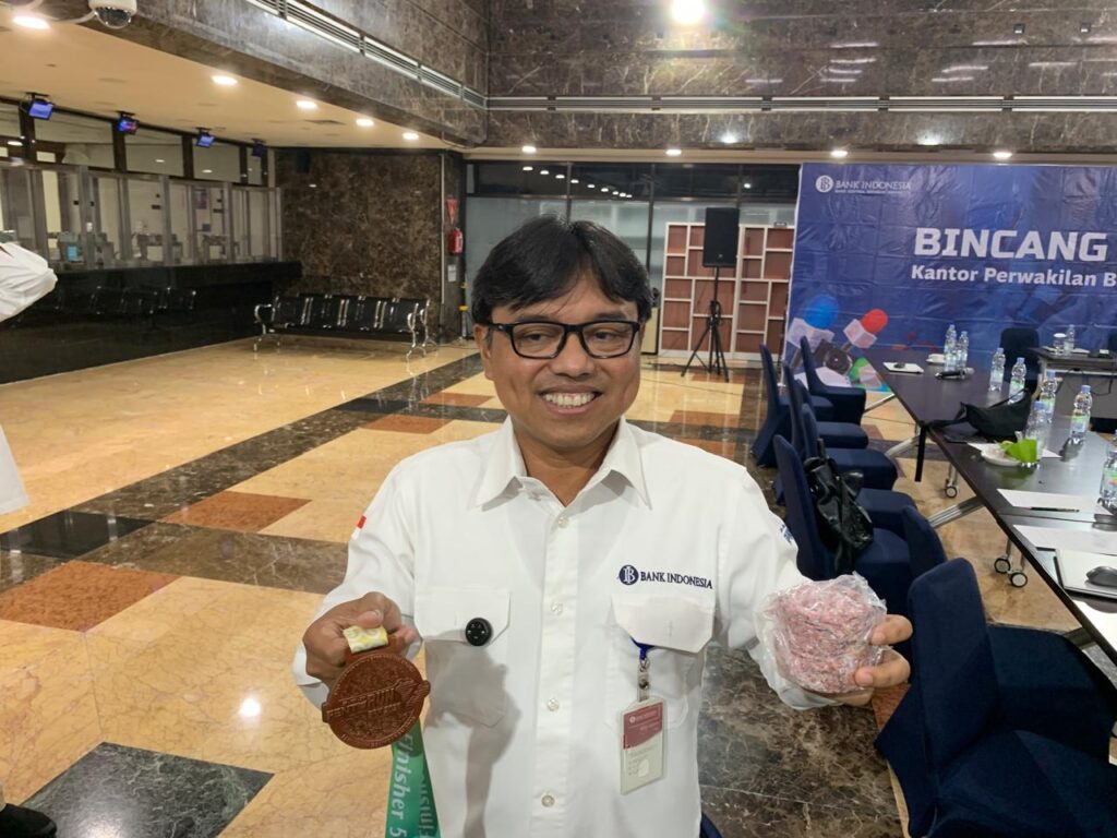 Kepala Kantor Perwakilan BI Balikpapan Robi Ariadi memegang medali dan uang tidak layak edar sebagai bahan pembuatan medali pada event FENTURUN 2026